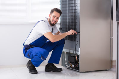 technician fixing refrigerator